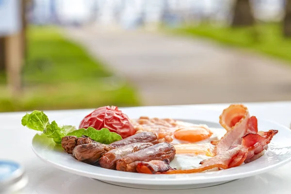 Traditional English breakfast with sunny side up egg,toast,tomatoes,bacon,sausage and baked beans. — Stock Photo, Image