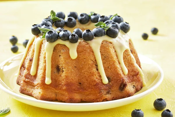 Blueberry bundt cake with icing on a yellow background — Stock Photo, Image