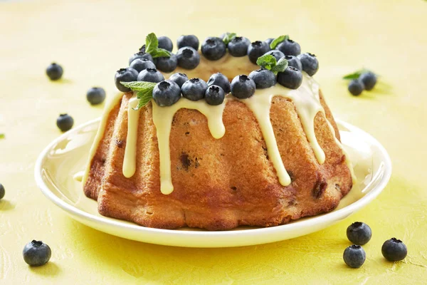 Blueberry bundt cake with icing on a yellow background — Stock Photo, Image