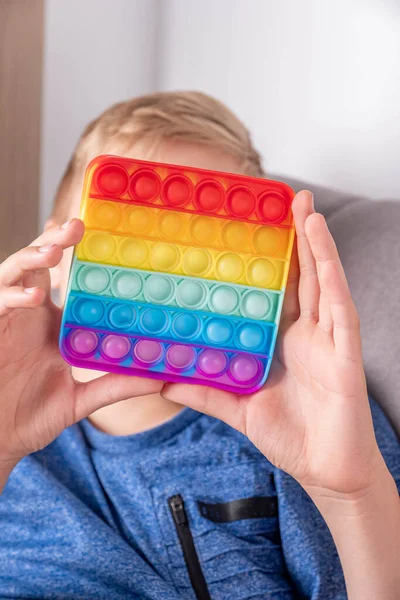 Cute faceless child playing with the Pop It fidget.