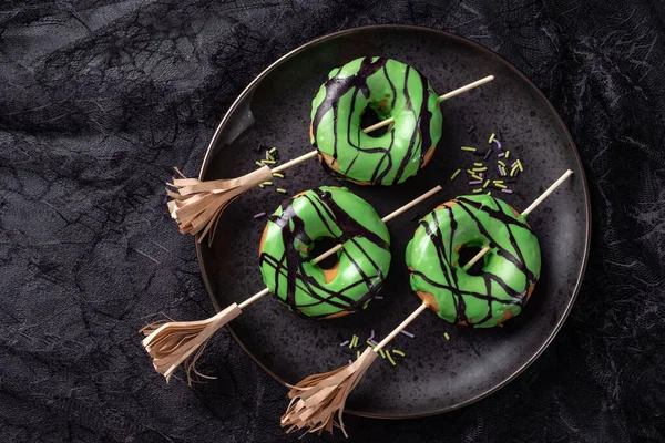 Halloween-Donut mit grüner Glasur und Hexenbesen. Süßes oder Saures. — Stockfoto