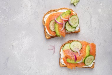 Krem peynirli çavdar ekmekli sağlıklı tost, somon, salatalık ve kırmızı soğan.