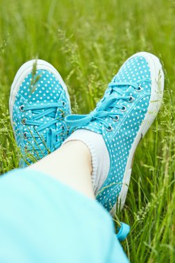 Yeşil çimenlerin üzerinde spor ayakkabı ayaklarda