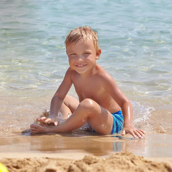 Menino sentado na praia — Fotografia de Stock