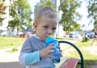 Little boy drinking water on a playground
