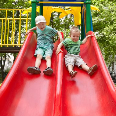 Two brothers sitting on slide