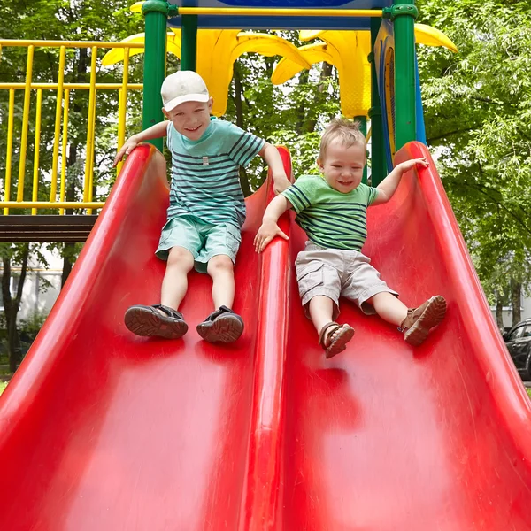 Two brothers sitting on slide — ストック写真