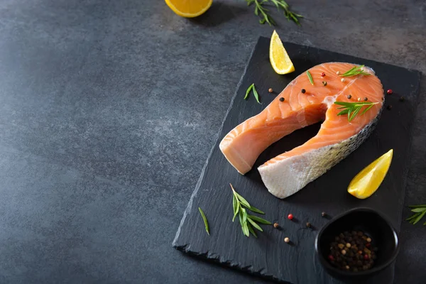 Fish restaurant menu. Fresh salmon or trout steak with salt, pepper, lemon and rosemary on a board on a white background. mediterranean cuisine, keto diet, seafood web line. Side view, copy space