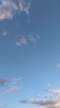 Pofuduk beyaz bulutlar hızla hareket ediyor. İdealik bulutlu cennet arka planı. Akşamları mavi gökyüzünde güzel bulutların zamanı. Gün batımı, mavi saat. Dikey video.