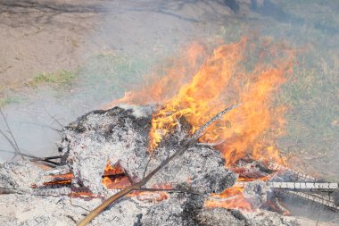 Açık havada büyük bir şenlik ateşi. Yanmış tahta ve dallardan bir kül yığını. Sıcak alev.