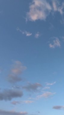 Pofuduk beyaz bulutlar hızla hareket ediyor. İdealik bulutlu cennet arka planı. Akşamları mavi gökyüzünde güzel bulutların zamanı. Gün batımı, mavi saat. Dikey video.