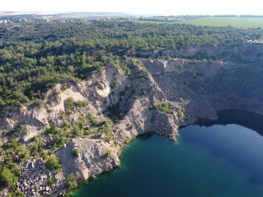 Güneşli bir yaz sabahında Radon Gölü 'nün Rocky kıyısında. Sel basmış eski bir granit ocağının hava manzarası. Resimli bir gölet..