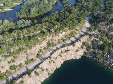 Güneşli bir yaz sabahında Radon Gölü 'nün Rocky kıyısında. Sel basmış eski bir granit ocağının hava manzarası. Resimli bir gölet..