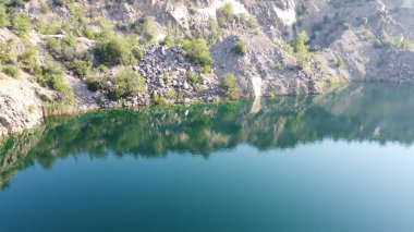 Güneşli bir yaz sabahında Radon Gölü 'nün Rocky kıyısında. Sel basmış eski bir granit ocağının hava manzarası. Resimli bir gölet..