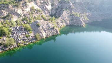 Güneşli bir yaz sabahında Radon Gölü 'nün Rocky kıyısında. Sel basmış eski bir granit ocağının hava manzarası. Resimli bir gölet..