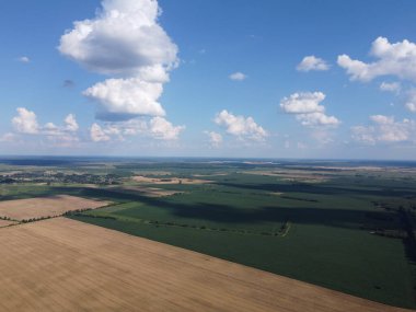 Güzel tarımsal manzara, açık arazi mavi gökyüzü ve beyaz bulutlar. Kuş bakışı tarlalar.