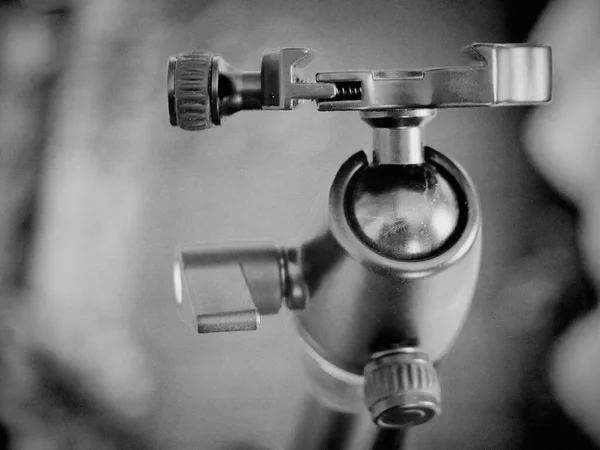 Tripod kameraya doğru gidiyor, yakın plan. Tripod başı, desteklenen aygıtı tripod bacaklara bağlayan tripod sisteminin bir parçasıdır..