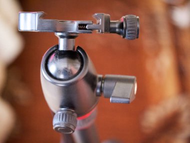 Tripod kameraya doğru gidiyor, yakın plan. Tripod başı, desteklenen aygıtı tripod bacaklara bağlayan tripod sisteminin bir parçasıdır..