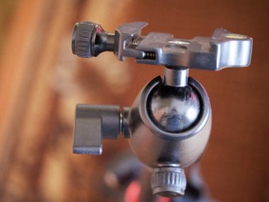 Tripod kameraya doğru gidiyor, yakın plan. Tripod başı, desteklenen aygıtı tripod bacaklara bağlayan tripod sisteminin bir parçasıdır..