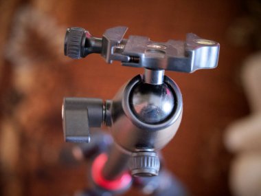 Tripod kameraya doğru gidiyor, yakın plan. Tripod başı, desteklenen aygıtı tripod bacaklara bağlayan tripod sisteminin bir parçasıdır..