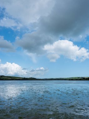 The waters of West Cork, Ireland, are beautiful and green. During the day, they are under a dramatic cloudy sky.