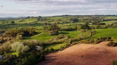 Yukarıdan, yeşil tarlaları ve çitlerle bölünmüş tarlaları görebilirsiniz, parçalı bulutlu bir gökyüzünün altında, kırsal Batı Cork, İrlanda.
