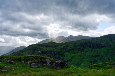 Bir dağ sırasının nefes kesici manzarası. Parlak gökyüzünün altındaki yemyeşil tepeler ve vadiler. Seyahat broşürleri, takvimler ya da doğa belgeselleri için mükemmel..