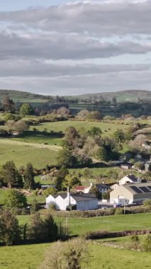 West Cork, İrlanda, 3 Mayıs 2025. Huzurlu tarım arazisi manzarası, manzarayı noktalayan evler.