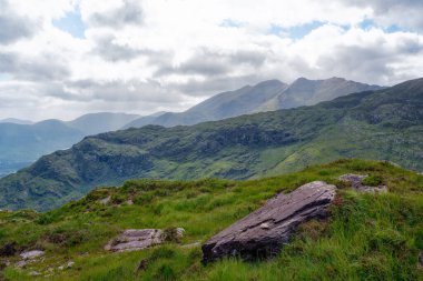 Sakin dağ manzarası. Yuvarlanan tepeler ve huzurlu bir atmosfer. Çimlerin üzerinde yalnız bir kaya dinleniyor.