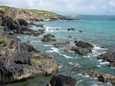 Kayalık sahilli sakin bir okyanus manzarası. Açık gökyüzü ile güzel kıyı manzarası.