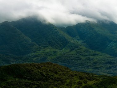 Yeşil dağların manzarası, Coomloughra At nalı, ve manzara boyunca yürüyüş patikaları. Bulutlar dağların zirvelerinden geçiyor..