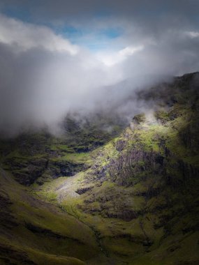 Canlı yeşil yosunlarla bezenmiş engebeli bir dağ yamacı gökyüzüne doğru yükseliyor. Bulutların zirvesinde sisli bir kucaklaşmayla dans ettiği yere..