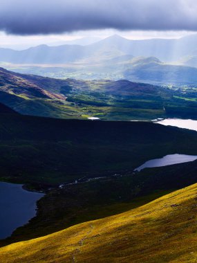 Killarney Gölleri ve yeşil tepelerin yer aldığı manzara bulutlu bir günde İrlanda 'nın Kerry ilçesinde hafif ışıkla yıkandı.