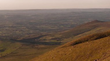Tepeler ve tarlalar altın ışıkta. Kırsal arazinin havadan görünüşü.