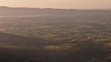 Tepeler ve tarlalar altın ışıkta. Kırsal arazinin havadan görünüşü. Kırsaldaki Idyllic tarım arazisi.
