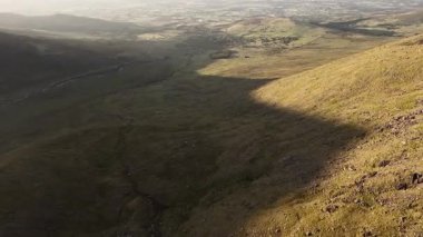Tepeler ve tarlalar altın ışıkta. Kırsal arazinin havadan görünüşü. Kırsal kesimdeki ideal tarım arazileri. Gün batımında Yuvarlanan Tepeler. Sıcak ışıkla yıkanmış vadi.