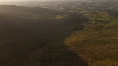 Tepeler ve tarlalar altın ışıkta. Kırsal arazinin havadan görünüşü. Kırsal kesimdeki ideal tarım arazileri. Gün batımında Yuvarlanan Tepeler. Vadi sıcak ışıkla yıkandı. Yukarıdan tarımsal arazi.