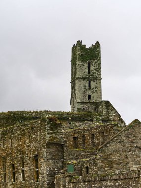 Timoleague, İrlanda, 25 Kasım 2023. Timoleague Keşişi. Antik taş manastırı parlak gökyüzüne karşı yıkıldı. Yosun ve ufalanan taşlarla yıpranmış ortaçağ kulesi.