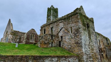 Timoleague, İrlanda, 25 Kasım 2023. Manastırın yıpranmış taş duvarları gri gökyüzüne karşı duruyor..