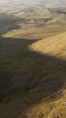 Tepeler ve tarlalar altın ışıkta. Kırsal arazinin havadan görünüşü. Kırsal kesimdeki ideal tarım arazileri. Gün batımında Yuvarlanan Tepeler. Vadi sıcak ışıkla yıkandı. Dağlı manzara.