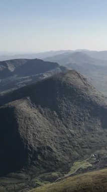 İrlanda 'nın Kerry ilçesindeki dramatik ve engebeli dağların gündüz görüntüsü uzak göl ve puslu manzarayı gözler önüne seriyor..