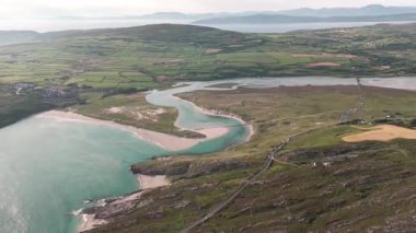 Muhteşem İrlanda kıyı şeridinin üzerinde uçuyor. Bir nehir güzel bir körfeze akar ve geniş bir kumsal oluşturur. Yeşil yama alanları ve uzak dağlar sakin gündüz manzarasını tamamlıyor.