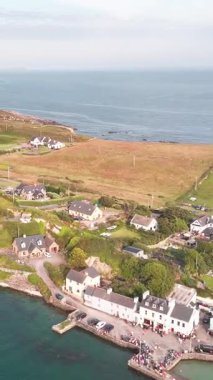 Bir köy manzarası ve İrlanda 'nın engebeli kıyı şeridi. Uçsuz bucaksız Atlantik Okyanusu kayalık, yeşil bir yarımadayla buluşur..