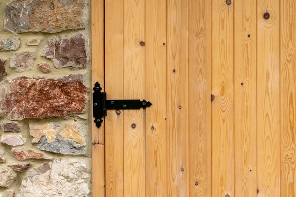 Taş binanın siyah menteşeli yeni ahşap kapısı. Boşluğu kopyala