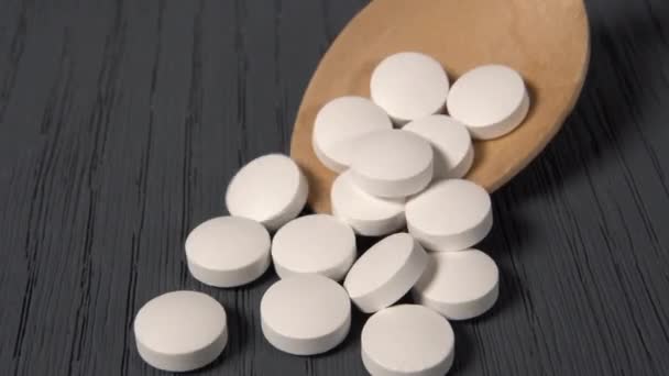 Белые Медицинские Таблетки Выливающиеся Деревянной Ложки Огромный Деревянный Стол Вблизи — стоковое видео