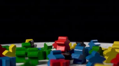 Ahşap bir yüzeydeki çeşitli renkli heykelcikler siyah arka planda dönerler. Ortadaki kırmızı biblo. Takım çalışması konsepti