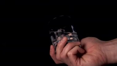 Elinde temiz su ve buz küpleri olan cam kaplama siyah arka planda. Parlak kristaller ve kabarcıklar