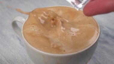 Bir avuç buz bir bardağa düşer ve üzerine su sıçratılır ve ahşap bir masaya dökülür. Kapatın. Yavaş çekim