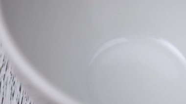 Beyaz tıbbi kapsüller beyaz bir seramik kaseye düşer. Yavaş çekim