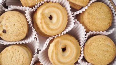 Açık metal bir teneke kutuda tereyağlı kurabiyelerin üst görüntüsü. Kağıt ambalajda İngiliz usulü tatlılar. Döndürme. Kapat.